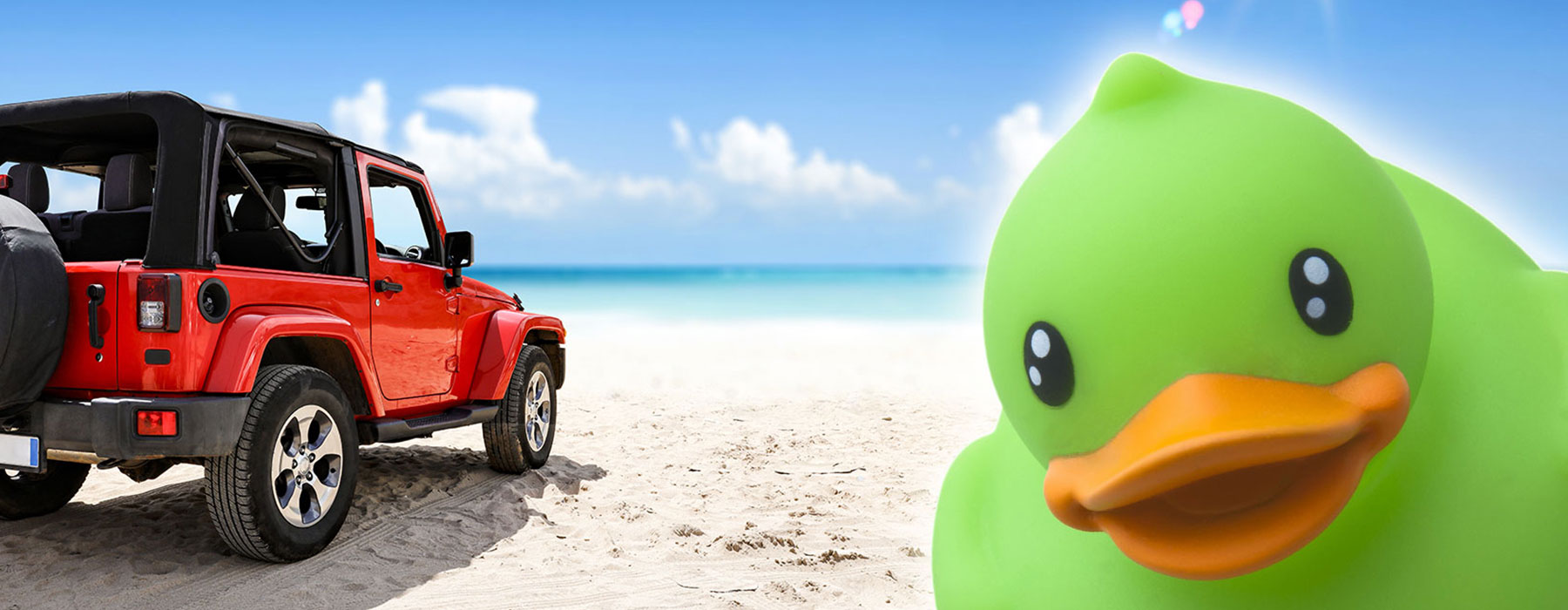 Jeep on beach with big green duck to the side